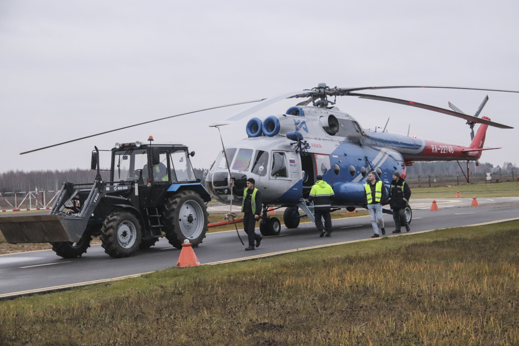 Вертолет Ми-8 к взлетной полосе доставляет трактор